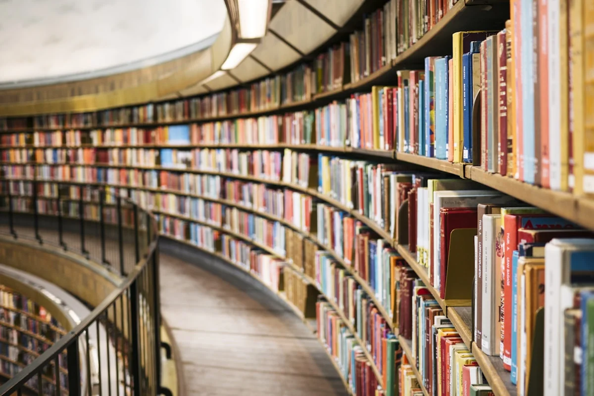 Floor-to-ceiling library shelving with warm amber light filtering through tall shelves