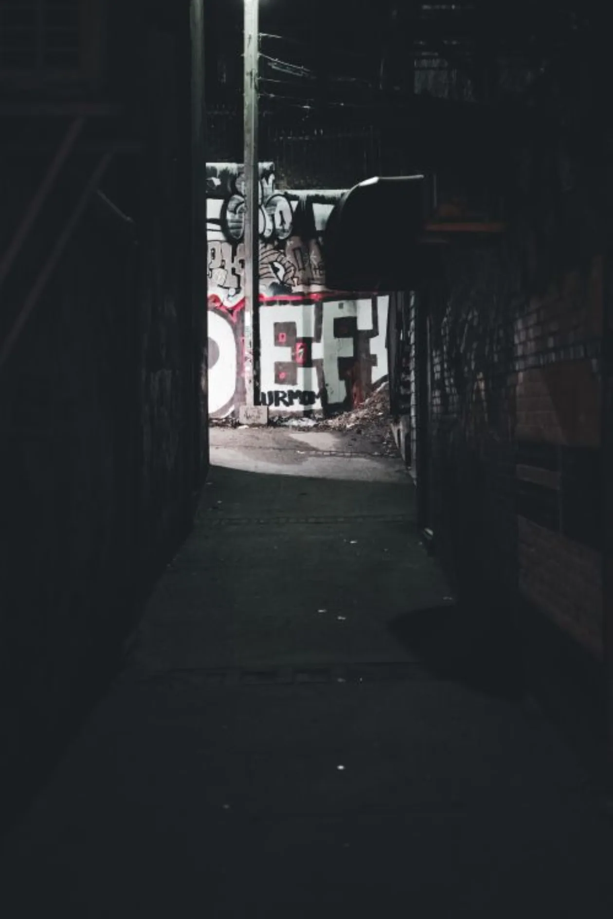 Light at the end of a dark narrow alley, dramatic perspective, single light source, deep shadows, film noir composition