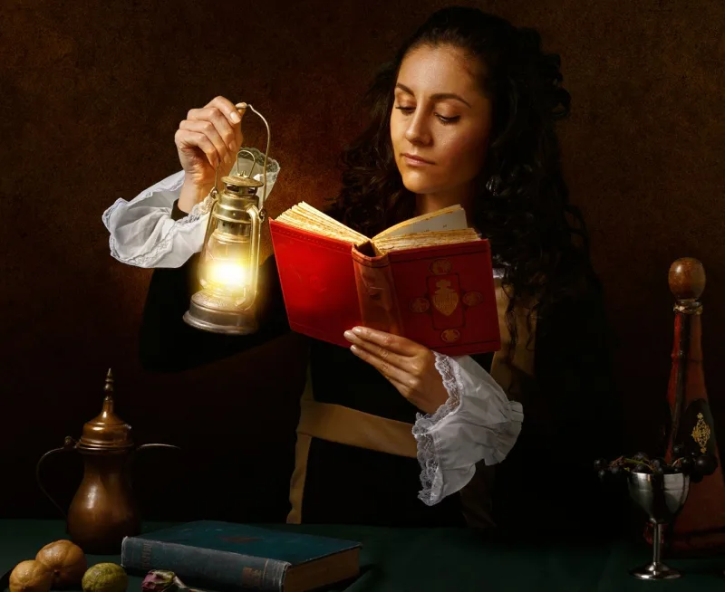 Woman in Victorian dress reading by oil lamp