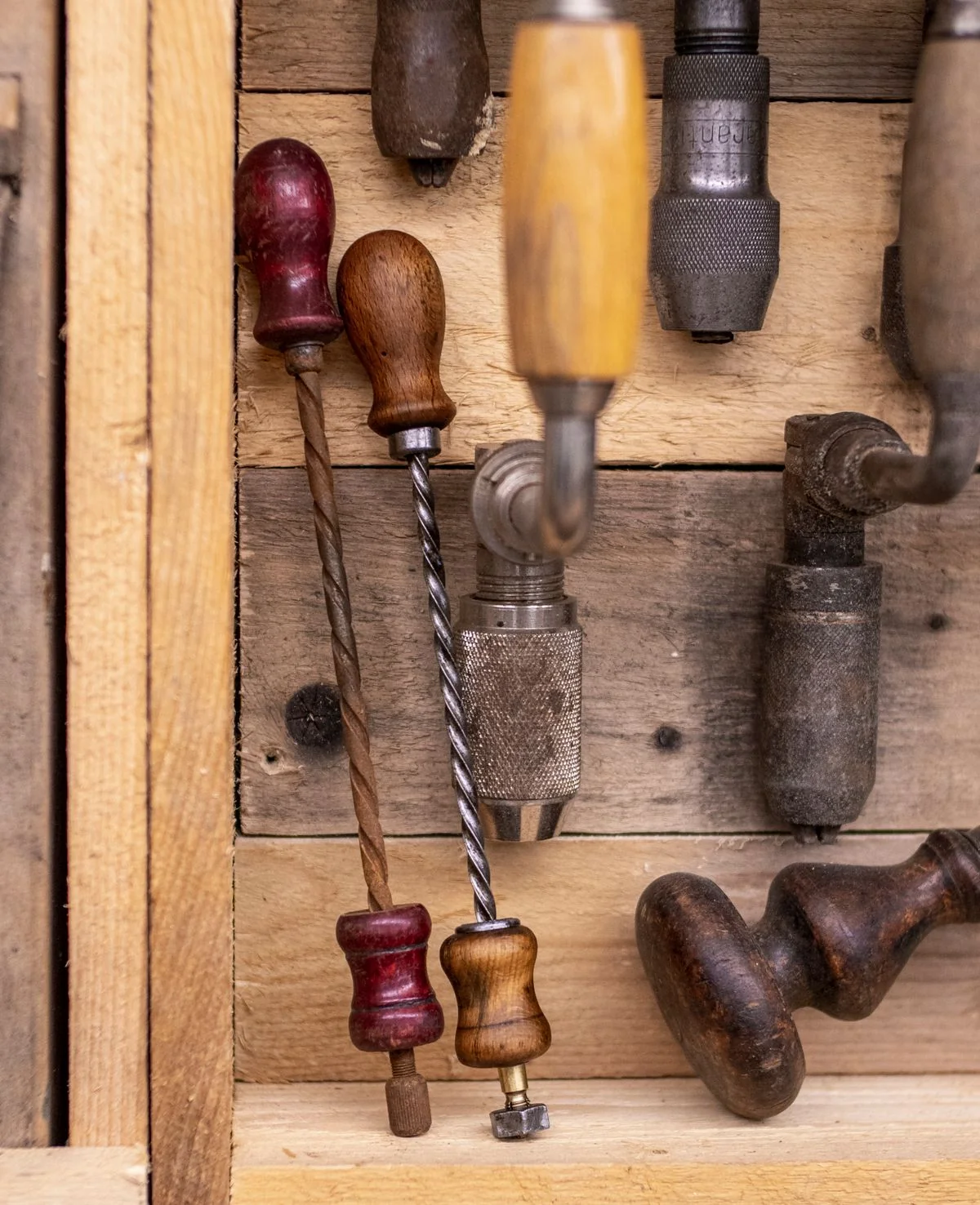A worn wooden workbench with brass tools — chisels, files, a small vice — morning light from a high window