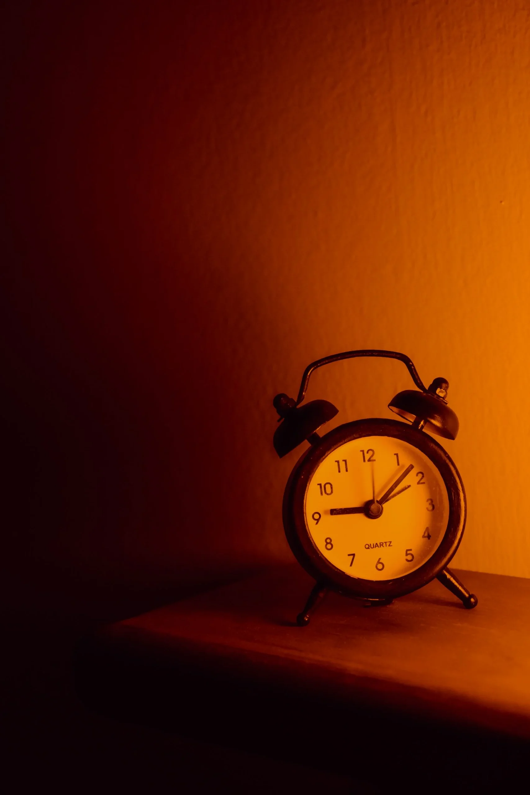 A clock face visible in near-darkness, the pendulum barely suggested in the shadows — time keeping going even when no one is watching, even when the remembering has stopped