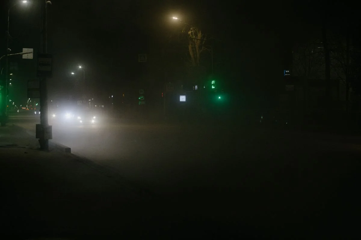 Fog-shrouded city street at night with amber streetlights glowing through the mist
