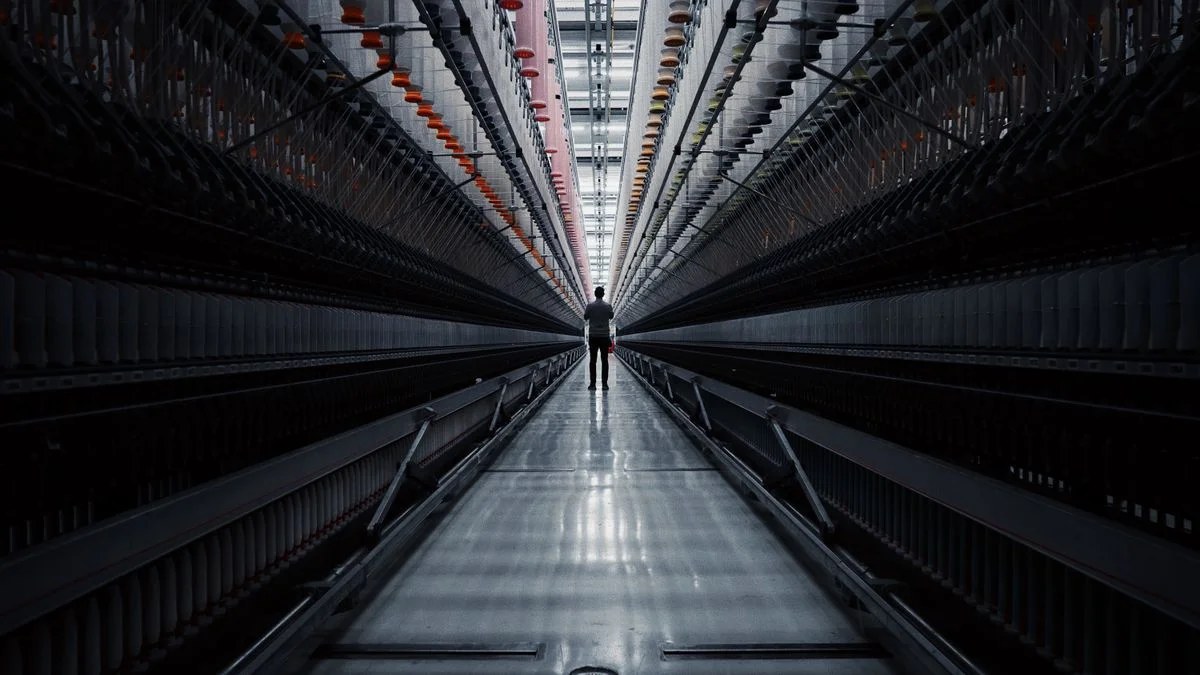Solitary figure standing in a vast industrial tunnel, a silhouette against distant light
