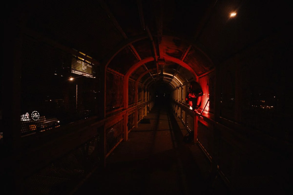 Industrial tunnel with red emergency lights cutting through the darkness