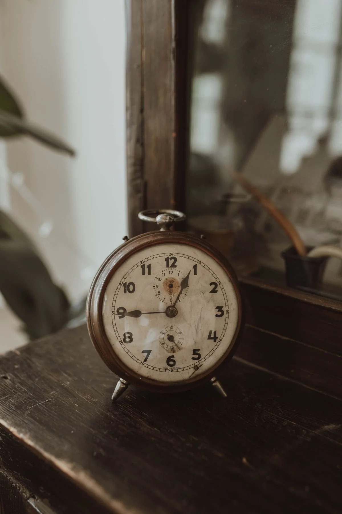 Close-up of an old brass clock face, hands frozen in place, warm light catching the patina
