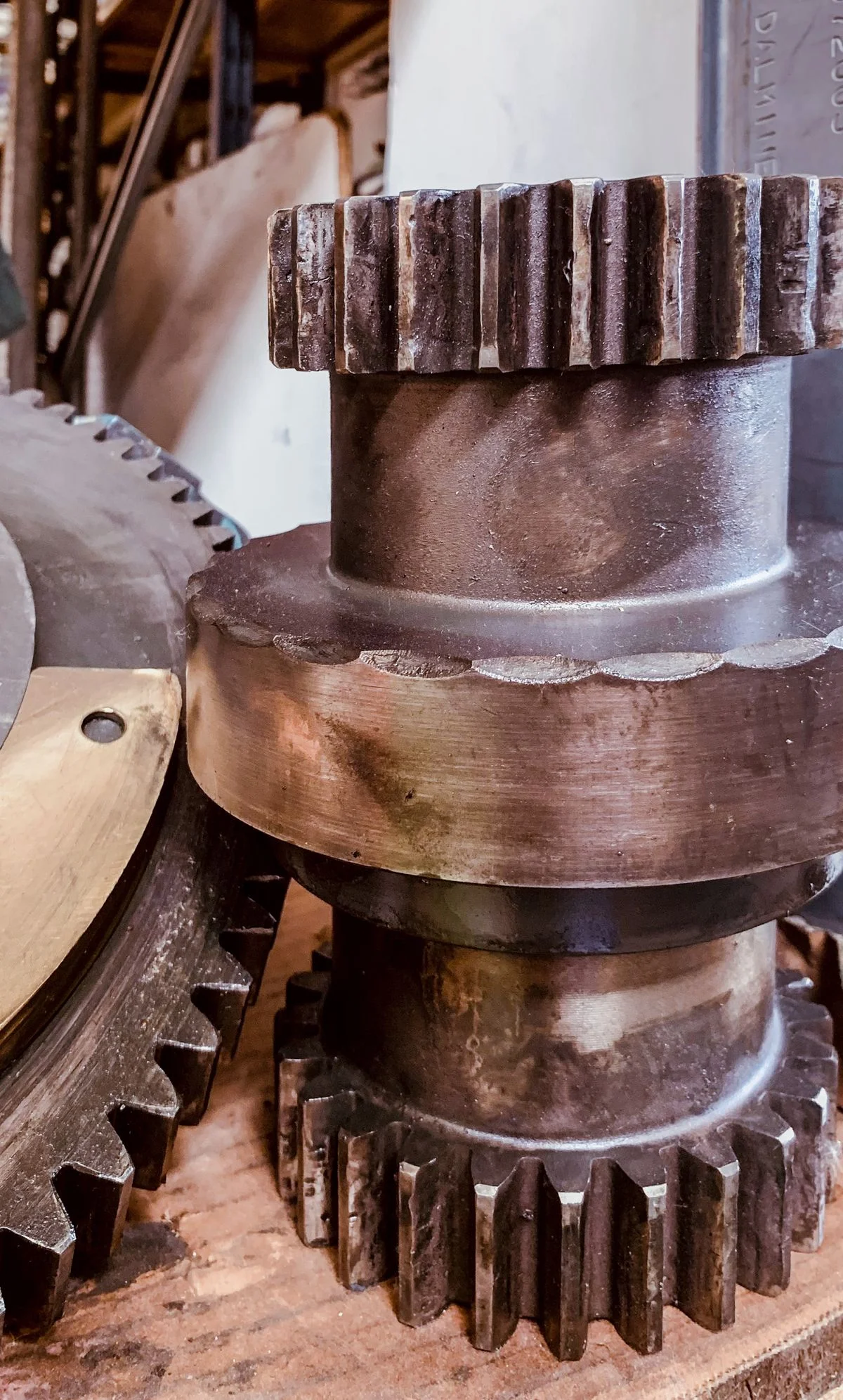 Close-up of antique brass gears in dark workshop, warm light catching the machined edges