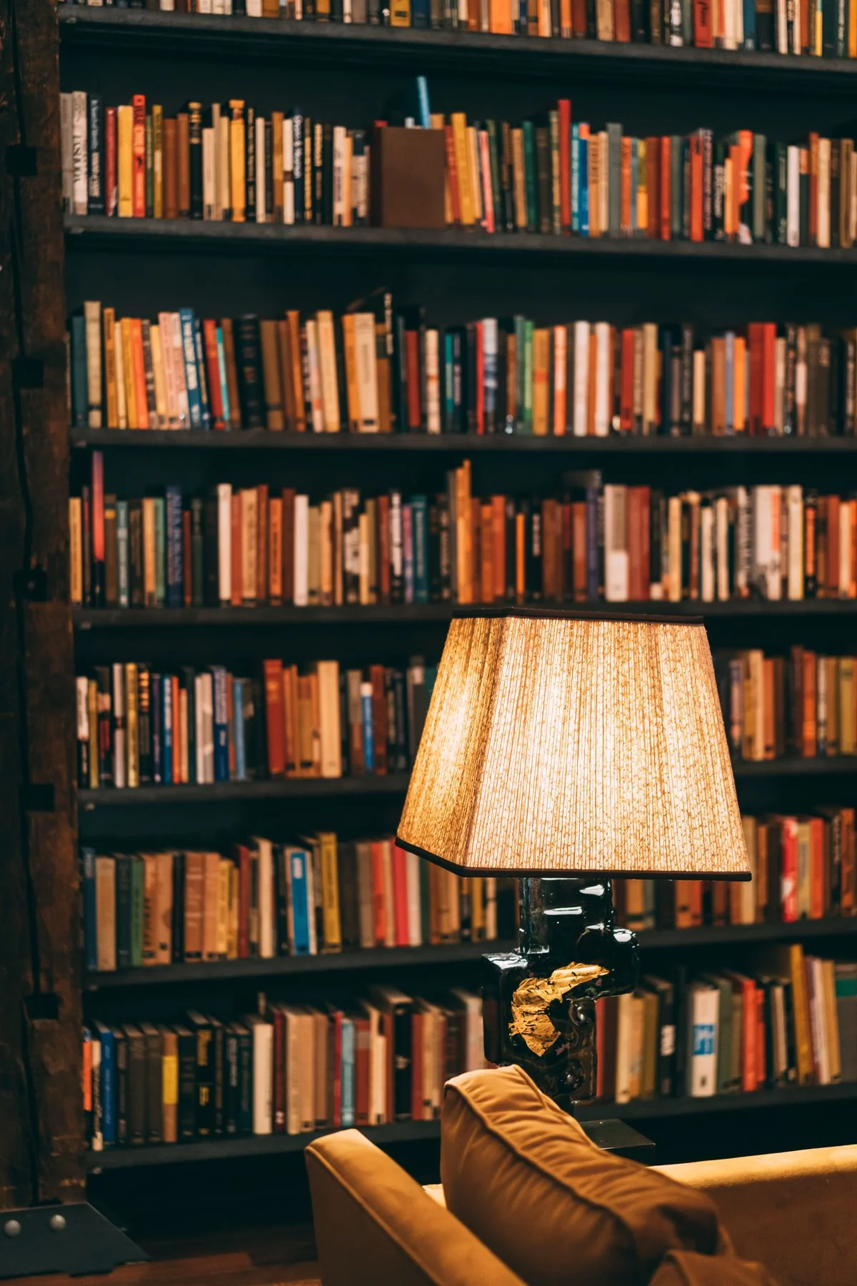 A warmly lit reading nook with old books, a leather chair, and soft lamplight