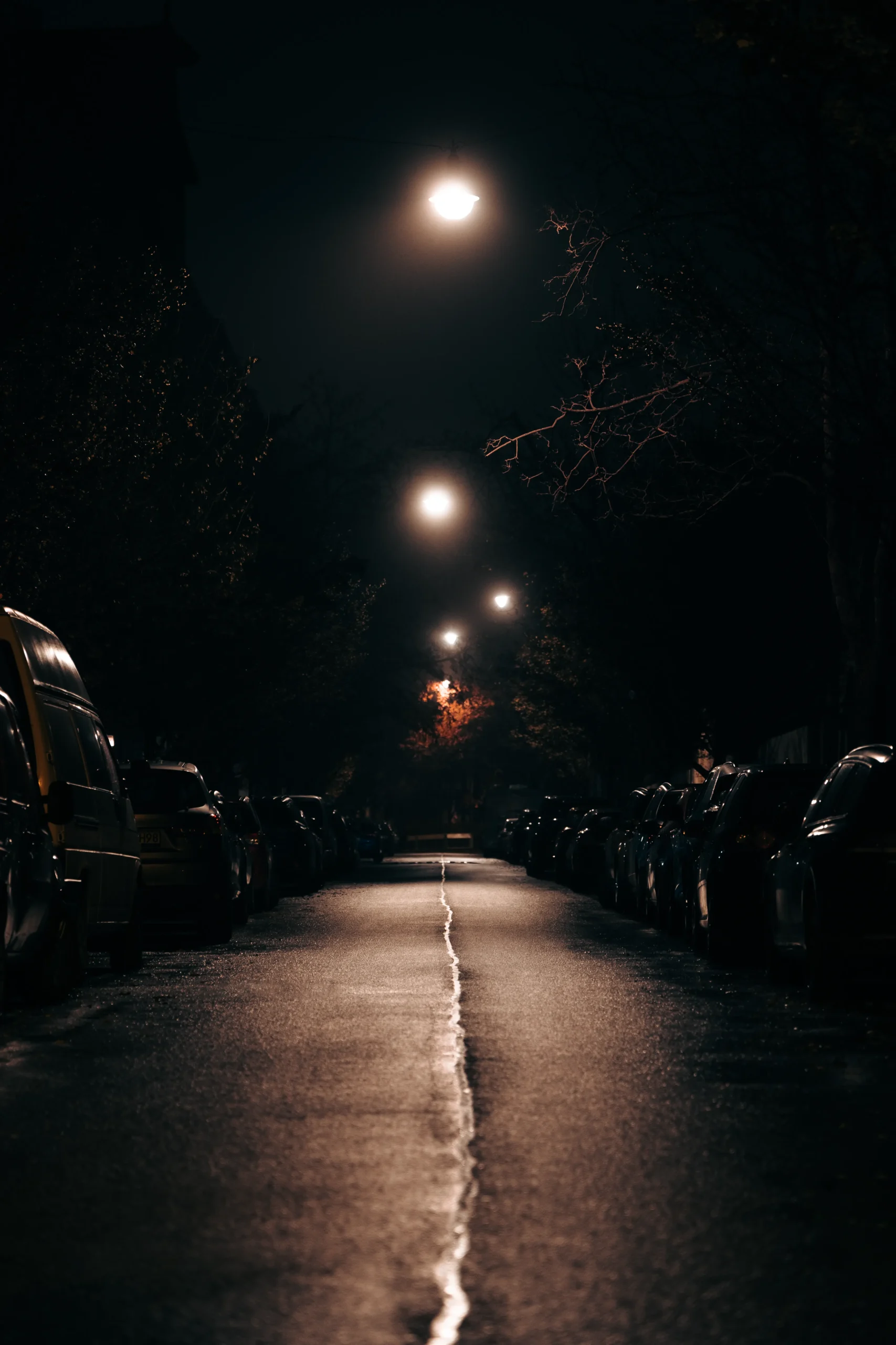 Moody urban street at night with dramatic lighting, rain glistening on the pavement
