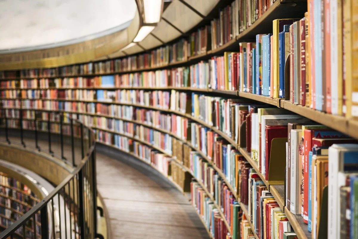 Stacks of weathered old books in a dim study — the accumulated cuckoos of human memory, catalogued and waiting