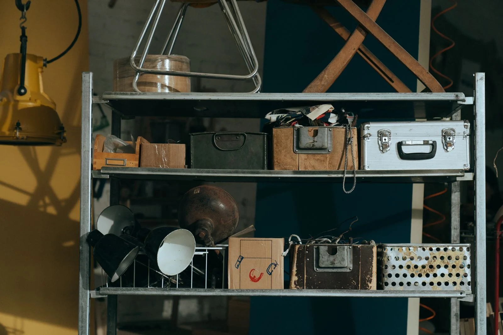 A workshop shelf in late summer — copper vessels, brass fittings, summer dust motes in the slanted light