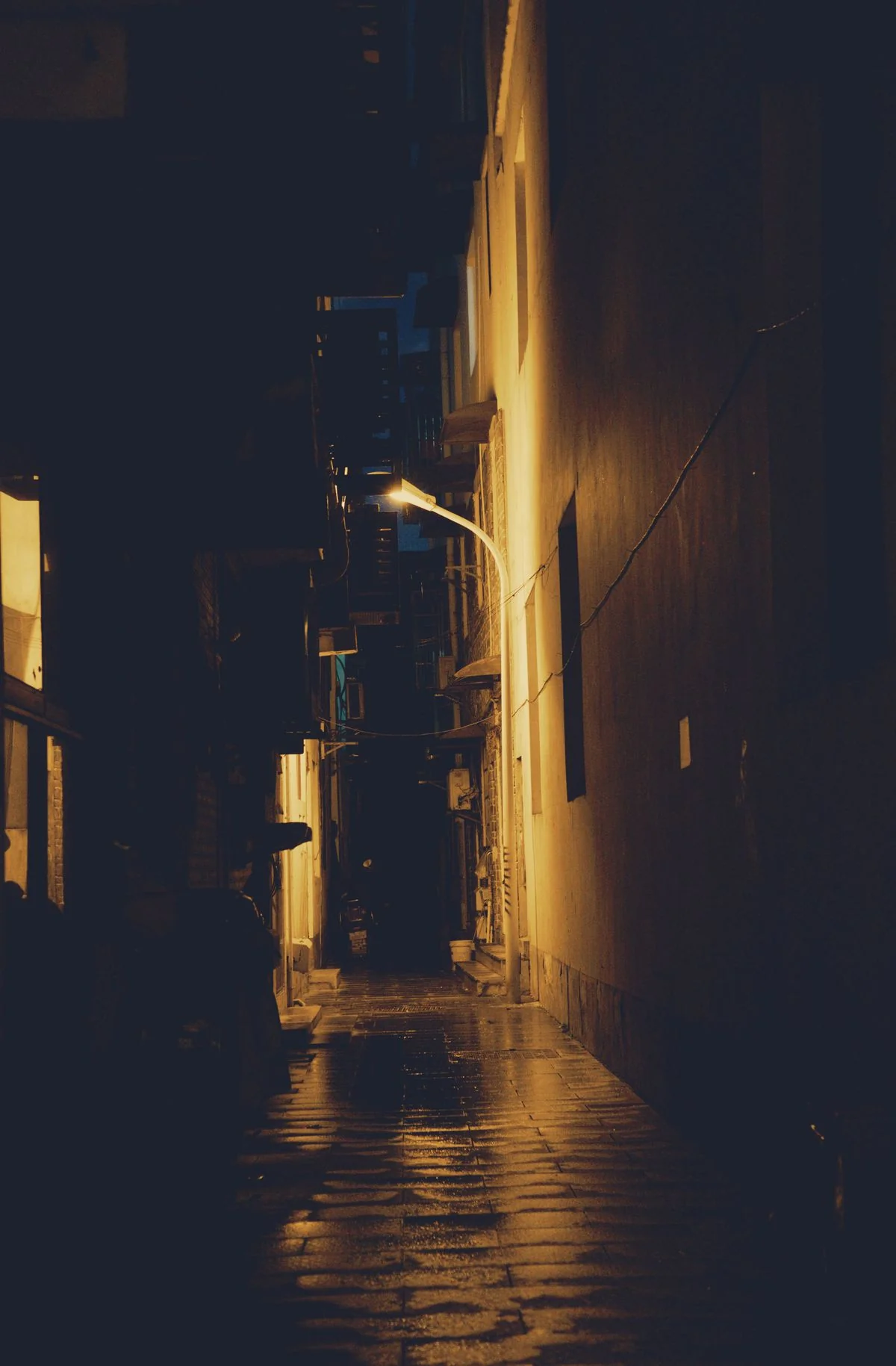 Single street lamp in a dark alley — noir mood of Dark City